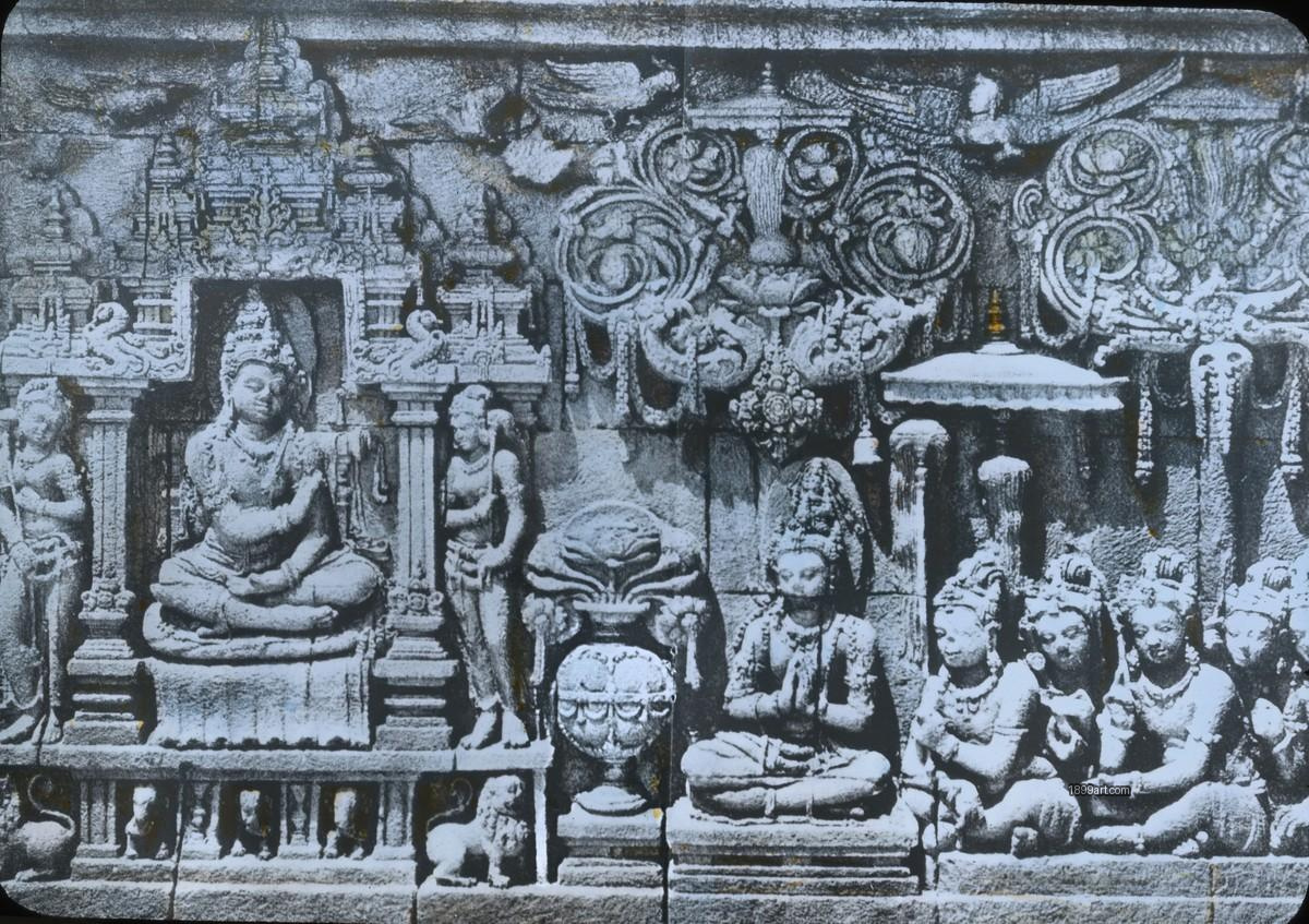 Handcolored stone relief shows carved seated and standing figures in a niche