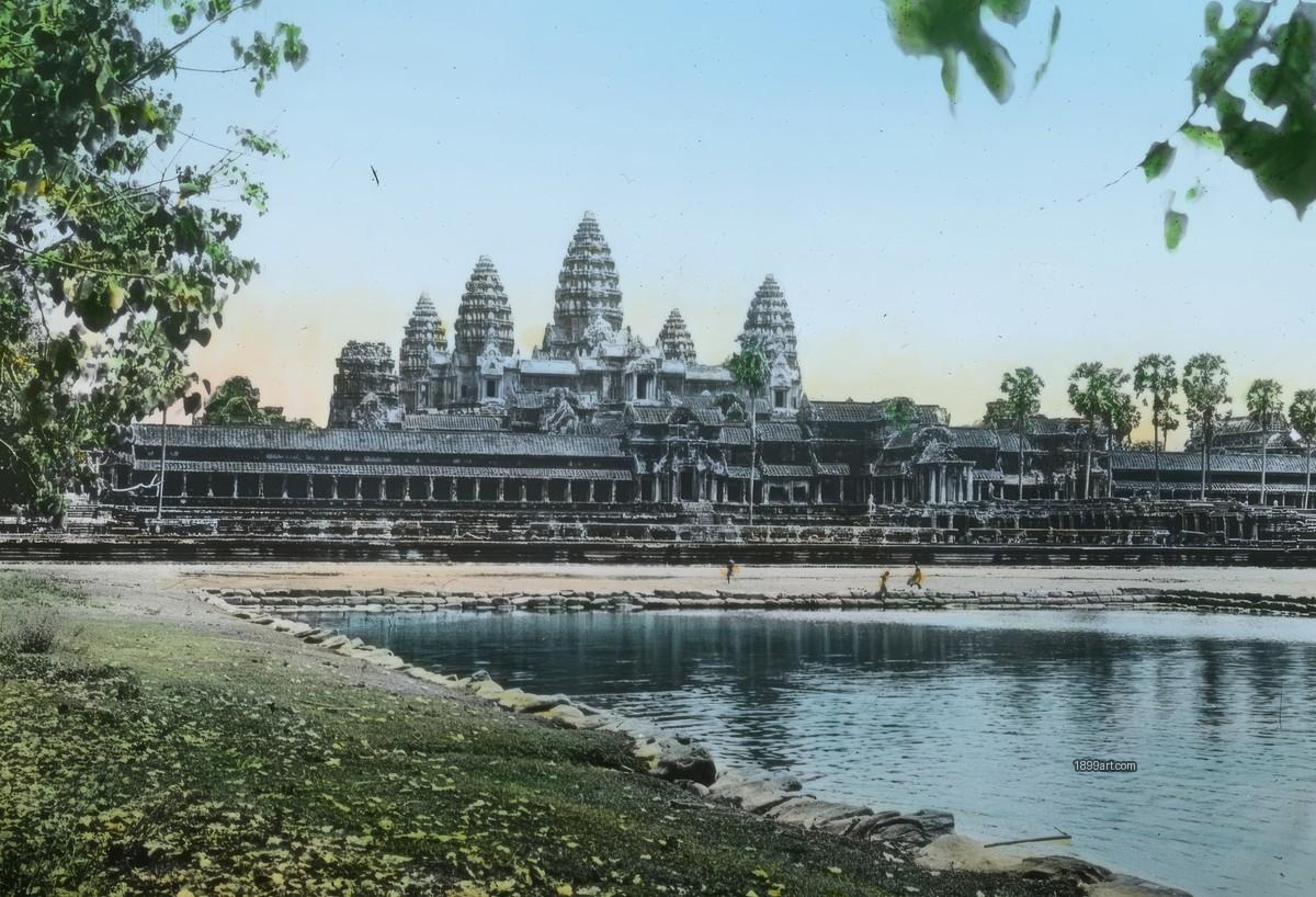 Angkor Wat towers beyond a moat, greenery, and a few walkers