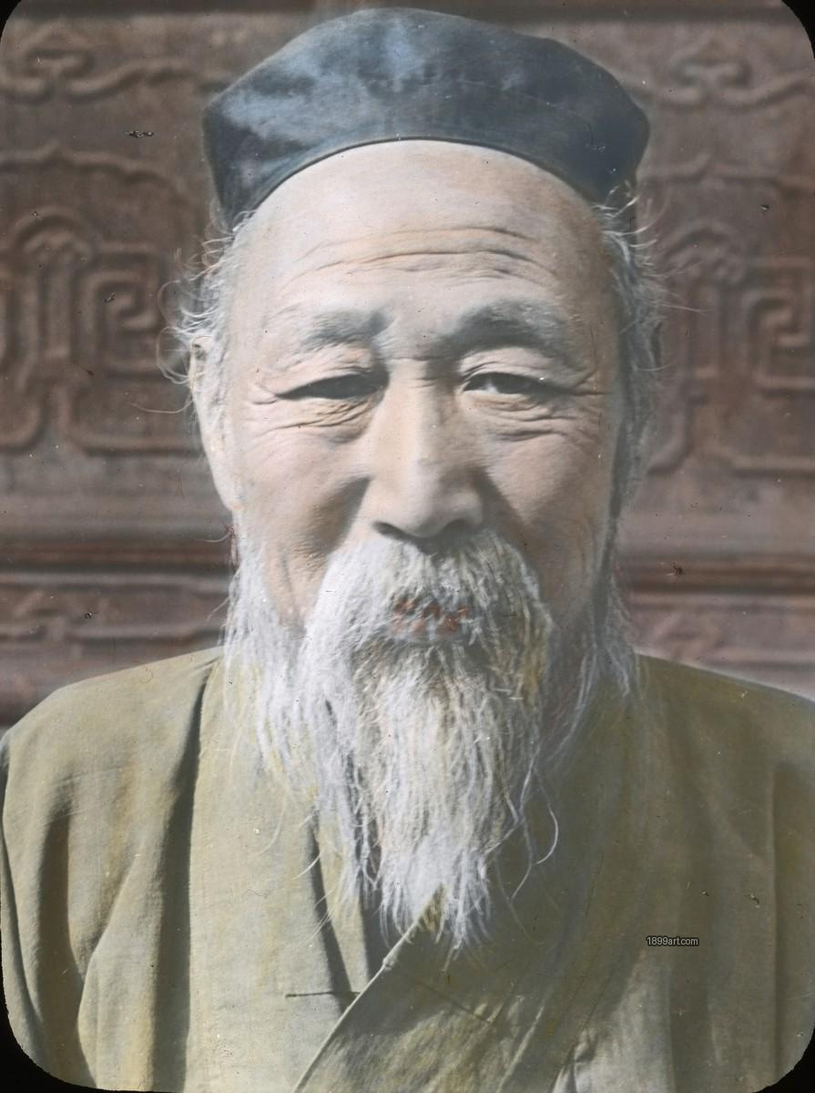 Elderly bearded man in dark cap before carved wooden background