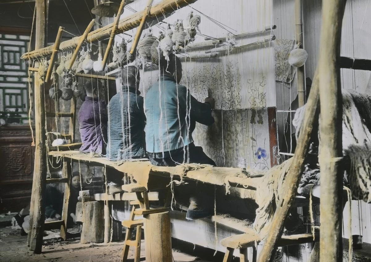 Three men weave on a large vertical loom in a rustic workshop