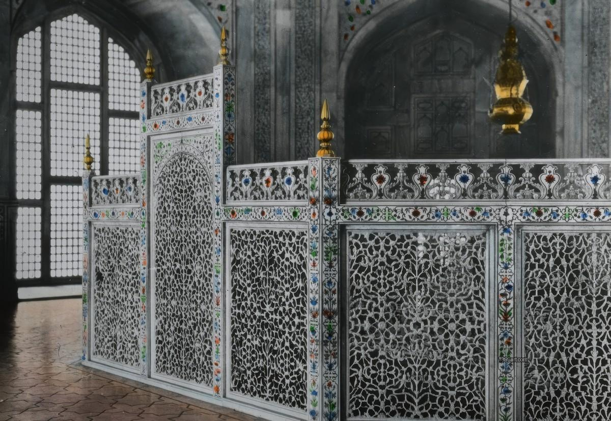 Carved marble jali screen with colorful floral inlays near arched window