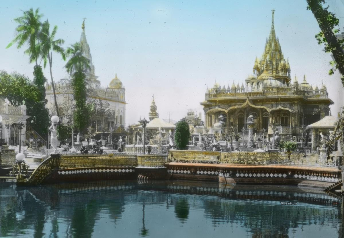 Ornate temple complex with gardens, palm trees, and a reflecting pool