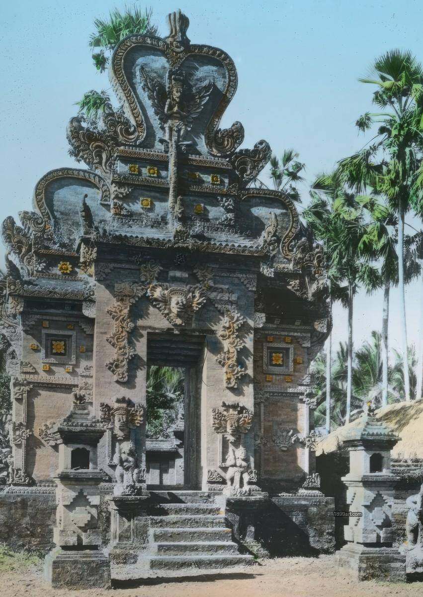 Handcolored stone temple gateway with carved figures, flanked by tall palms