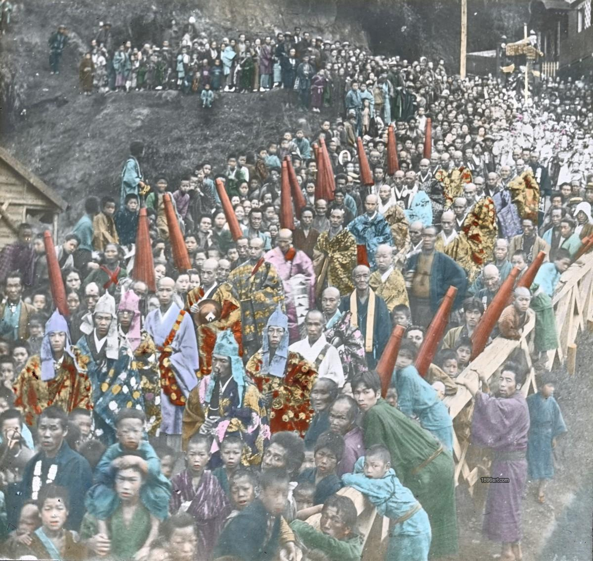 Monks and laypeople line a sloped path carrying long red objects