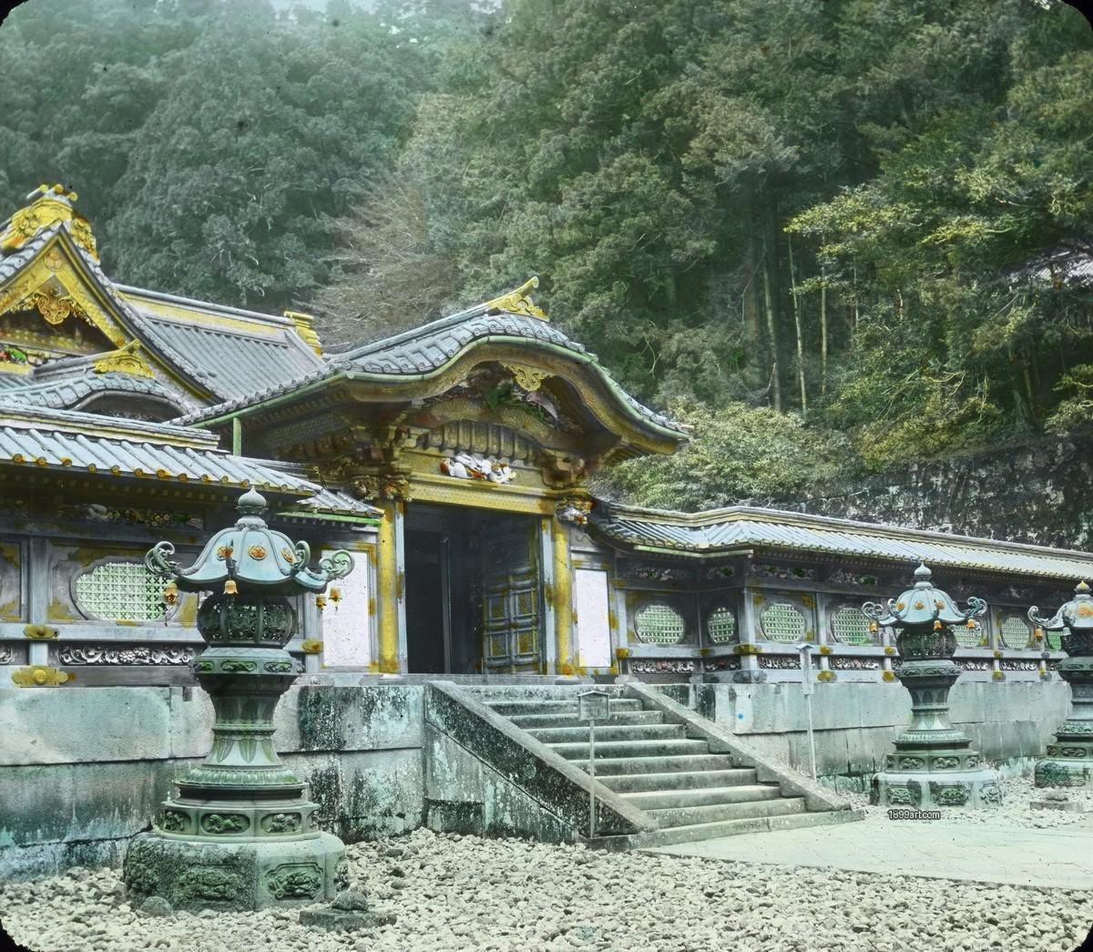 Ornate shrine entrance gate above stone steps, with three lanterns