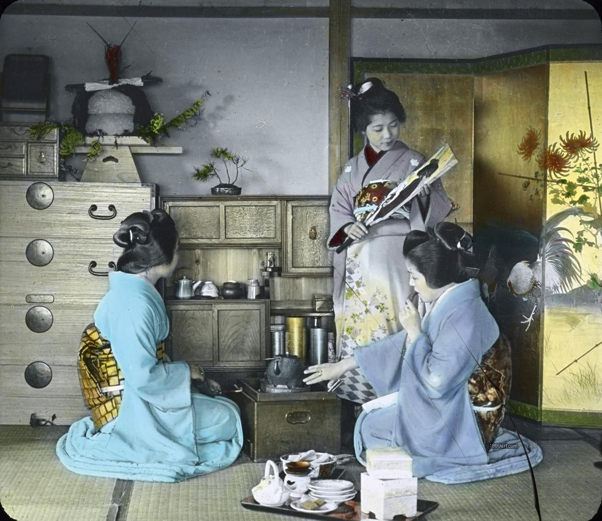 Three women in kimonos gather indoors around a small hearth