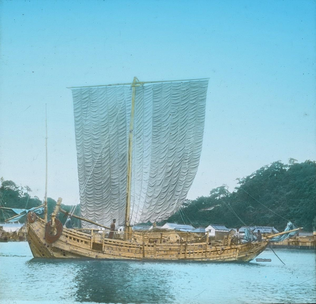 Traditional wooden sailboat with a large white sail and people aboard