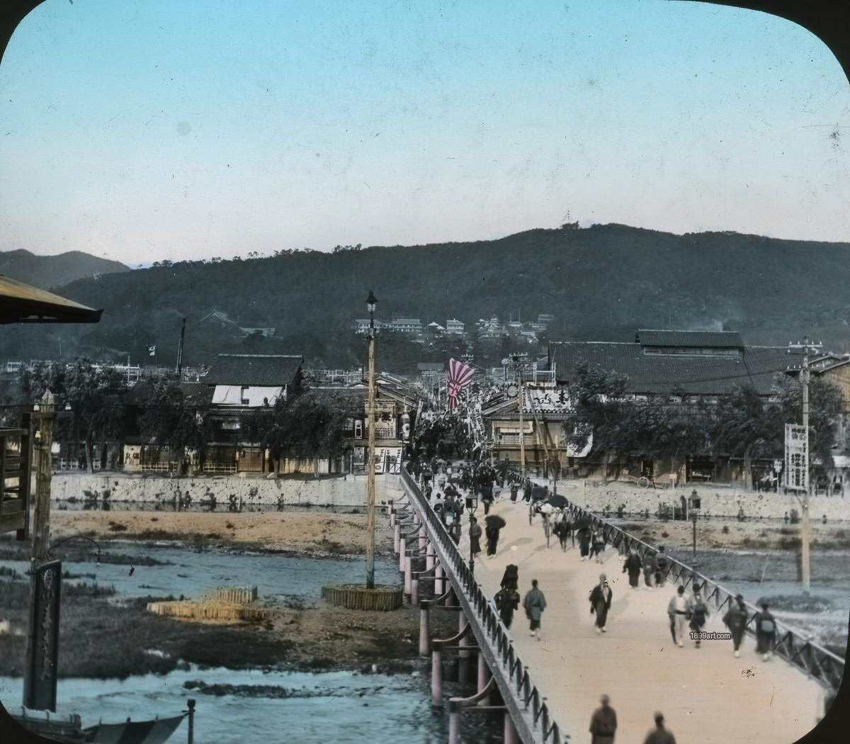 Crowded wooden bridge with people, horses, and carriages over a river