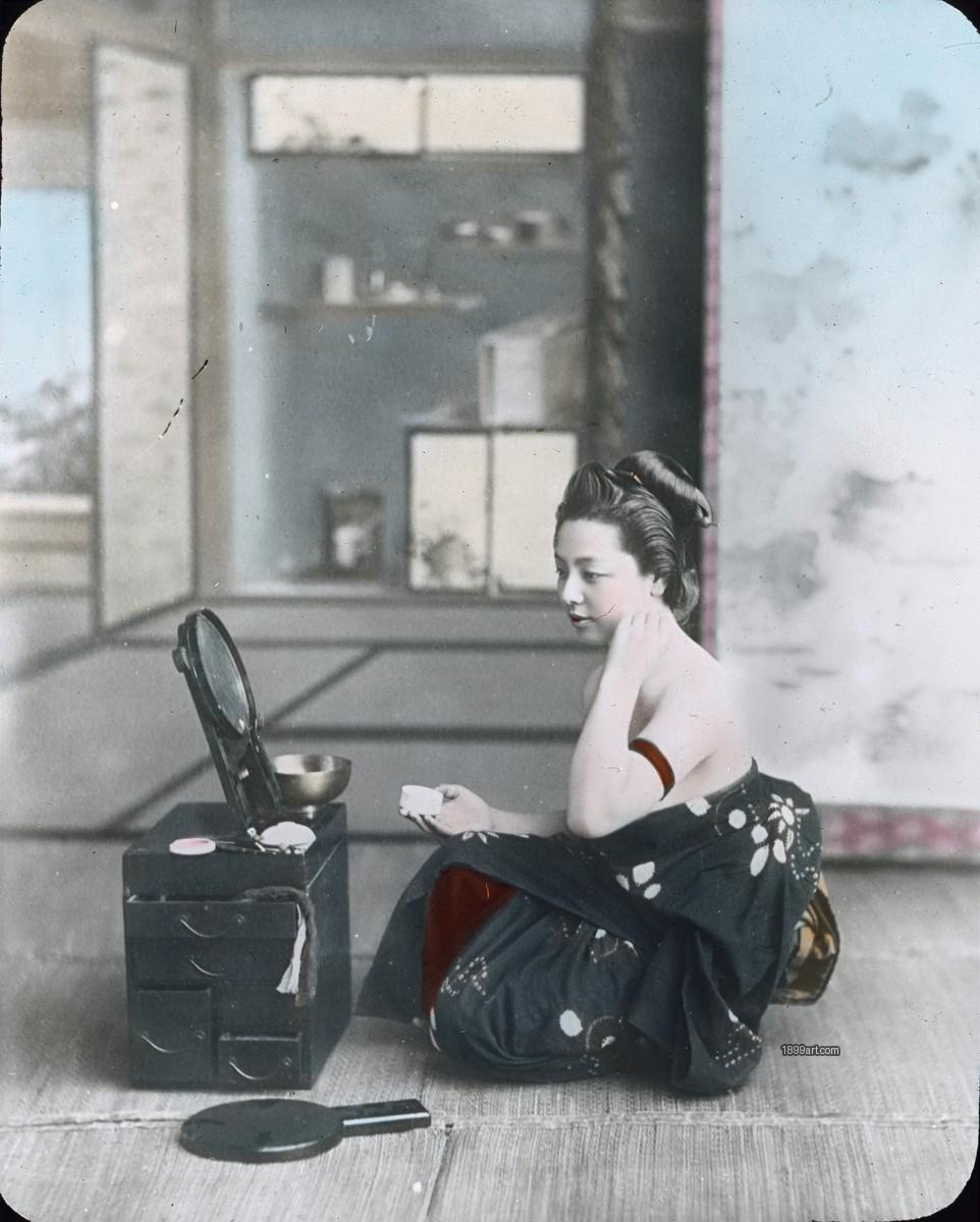 Japanese woman on tatami applies makeup using a small mirror
