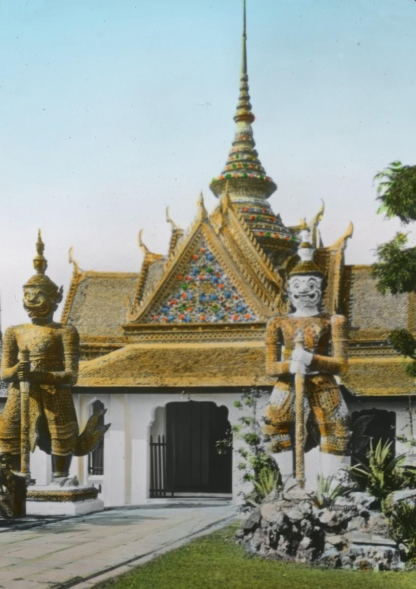 Two guardian statues with staffs beside a decorated temple entrance