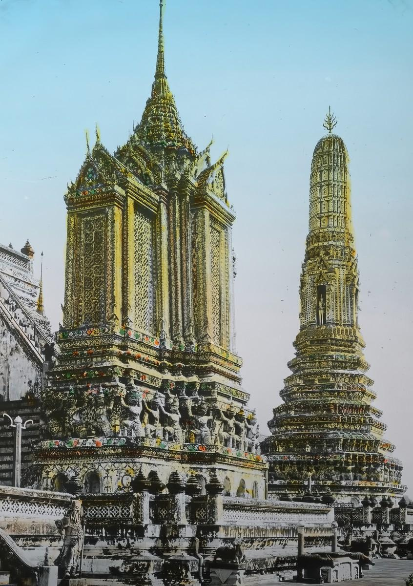 Two ornate Thai temple prangs with colorful decorations under a clear sky