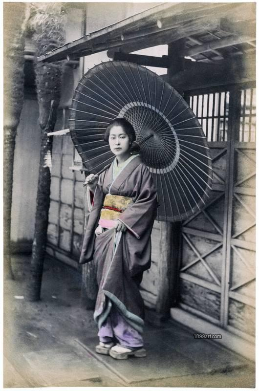 1899art Japan Woman with Paper Parasol in a Narrow Street Handcolored 1900s Enami 1899art. Historical photograph from the 1899art Archive.