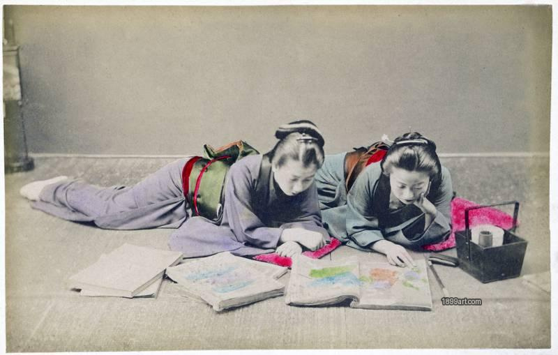1899art Japan Two maiko studying illustrated albums, studio scene attributed to the Yokohama School (possibly Kusakabe Kimbei) Handcolored 1900s 1899art. Historical photograph from the 1899art Archive.